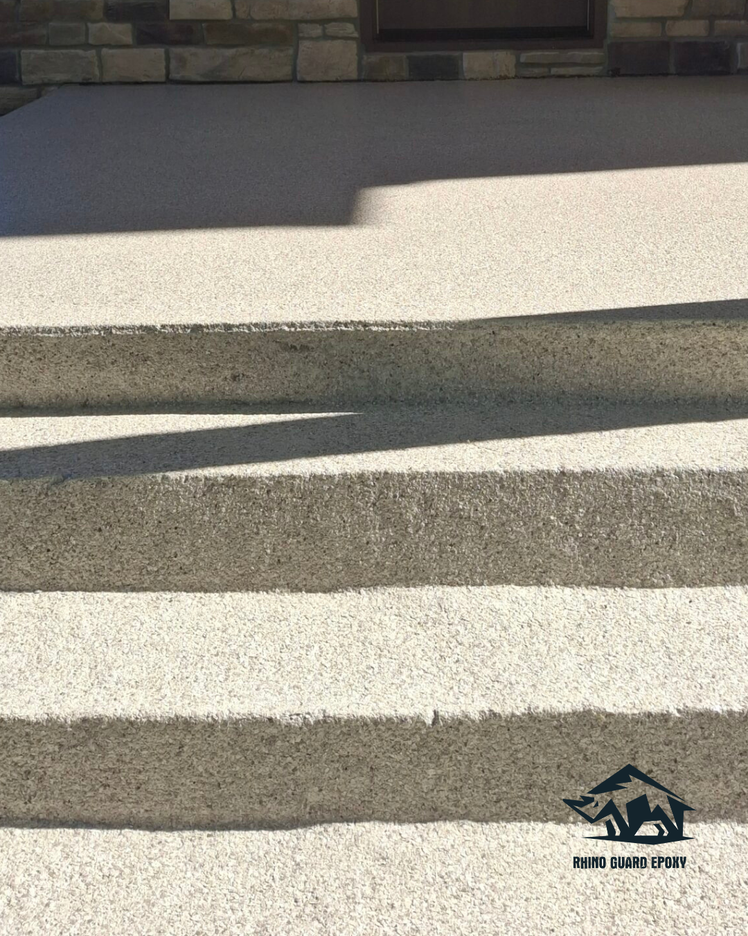 Exterior concrete stairs with pronounced shadows across each tread; Rhino Guard Epoxy logo in the lower-right corner.